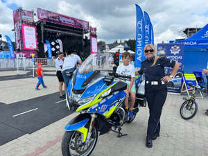 policjantka stojąca przy motocyklu służbowym na którym siedzi chłopiec