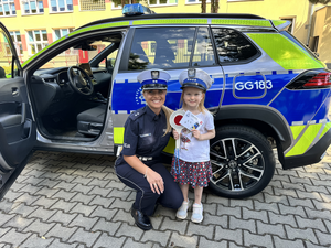 policjantka pozuje do zdjęcia z dziewczynką przy radiowozie