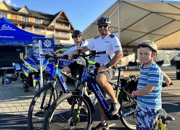 policjantka i policjant na służbowych rowerach, obok dziecko na swoim jednośladzie