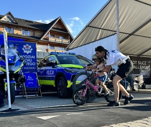policjantka pomaga dziecku jadącemu na rowrze