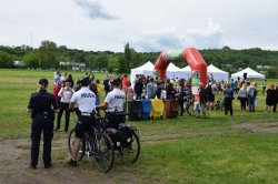 dwaj policjanci drogówki na rowerach służbowych obok policjantka prewencji w tle trwająca impreza na krakowskich Błoniach