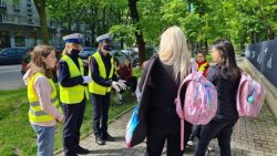 na chodniku przed szkołą policjantki rozmawiają z rodzicami uczniów o zmieniających się przepisach ruchu drogowego