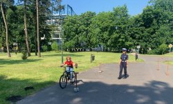 Dziecko w trakcie egzaminu praktycznego na kartę rowerową jadące na rowerze, po prawej stronie policjantka WRD KMP w Krakowie.