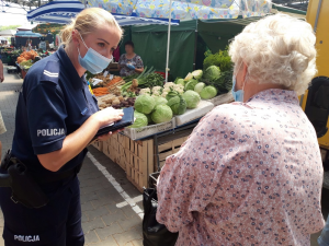 policjantka na placu targowym podczas rozmowy ostrzega kobietę przed oszustami