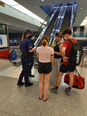 policjantki na terenie dworca kolejowego wręcza grupie podróżnych ulotki informacyjne z poradami