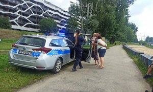 policjantka przy radiowozie na bulwarze wiślanym rozmawia ze spacerowiczami o bezpieczeństwie nad wodą