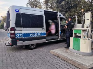 W radiowozie siedzi odnalezione dziecko, obok stoją policjanci