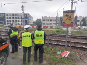 policjanci z pracownikami kolei w pobliżu dzikiego przejścia kolejowego