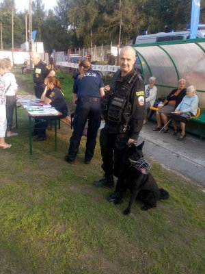 stoisko profilaktyczne obok policjantka oraz przewodnik z psem służbowym