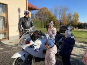 Dzieci przy policyjnym motocyklu obok stoi policjant drogówki