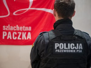policjant przy plakacie Szlachetnej Paczki
