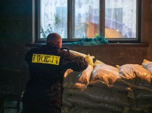 policjant układający worki z ekogroszkiem pod domem obdarowywanej rodziny