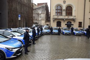 Policjanci stoją przy radiowozach na placu przed budynkiem Urzędu Miasta