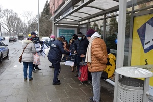 Policjanci rozdający kalendarze na przystanku autobusowym.