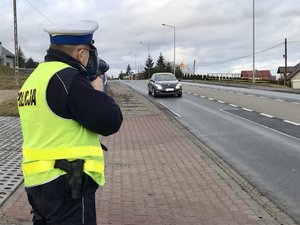 policjant ruchu drogowego mierzy prędkość jadącego pojazdu