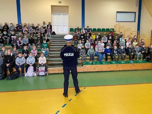 policjantka prowadzi prelekcję dla uczniów na sali gimnastycznej