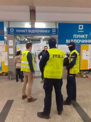 Policjanci rozmawiają z wolontariuszami pod punktem pomocy