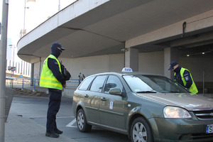 Dwaj policjanci rozmawiają z kierowcą TAXI