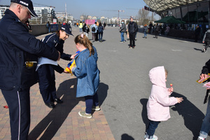 policjant z policjantką wręczają ukraińskiej dziewczynce słodycze