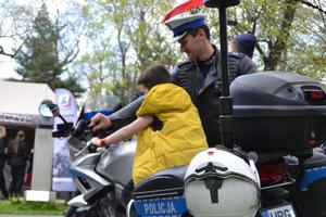 Chłopiec siedzący na motocyklu, obok stoi policjant