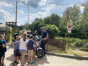 dzieci oglądają policyjny motocykl w towarzystwie policjanta z drogówki