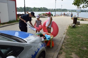 dziewczynki otrzymują od policjantki gadżety plażowe