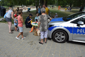 plażowicze z policjantką przy radiowozie