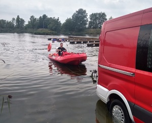 strażak płynie pontonem do brzegu