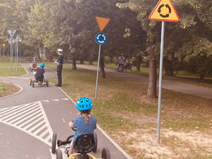 dzieci jeżdżące gokartami po miasteczku rowerowym w obecności policjantki