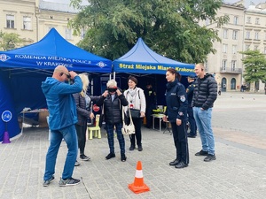 mieszkańcy i policjantka przy stoiskach profilaktycznych Policji i Straży Miejskiej na Rynku Głównym