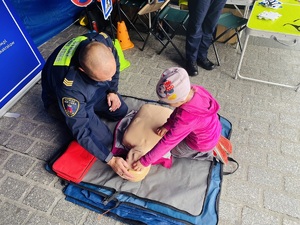 strażnik miejski przy fantomie, tłumaczy dziecku zasady udzielania pierwszej pomocy