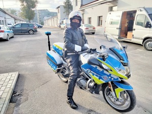 policjant siedzi na nowym motocyklu służbowym przed budynkiem, w tle samochody