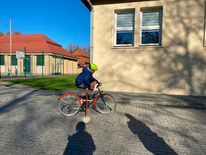 uczeń przed budynkiem szkoły pokonuje na rowerze tor przeszkód