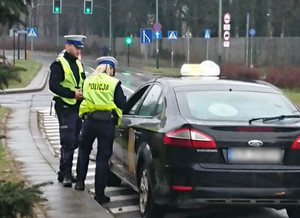 policjant i policjantka w czasie kontroli drogowej taksówki