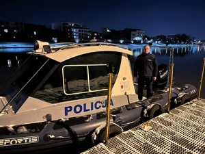 Policjant Komisariatu Wodnego Policji w Krakowie asp. szt. Rafał Zakrocki na tle łodzi służbowej