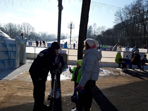 przy lodowisku policjantka wręcza dzieciom ulotki informacyjne