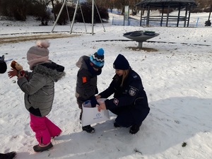 w parku dzieci dostają od policjantki drobne gadżety