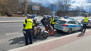 policjanci w trakcie kontroli kierujących motocyklami stojący za radiowozem na jednej z krakowskich ulic