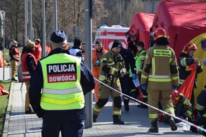 Dowodzący działaniami policjant idący w kierunku innych osób ze służb biorących udział w działaniach