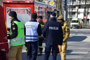 policjant stojący tyłem do zdjęcia prowadzący rozmowę z koordynatorem medycznym oraz strażakami