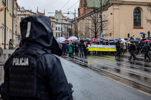 Na zdjęciu widać funkcjonariusza policji obeserwującego osoby uczestniczące w marszu