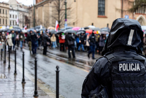 Na zdjęciu widać policjanta obserwującego uczestników zgromadzenia