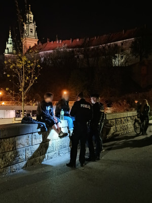 dwóch policjantów legitymuje dwie osoby. W tle widać krakowski Wawel