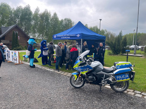 uczestnicy uroczystości przy policyjnym stoisku, na pierwszym planie policyjny motocykl