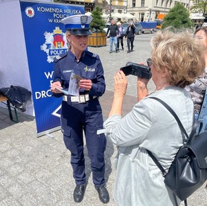 policjantka wręcza ulotkę osobom będącym na Rynku Głównym