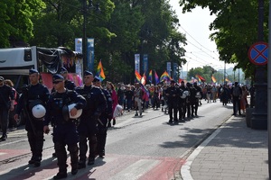 umundurowani policjanci idący obok uczestników marszu przez jedną z ulic Krakowa