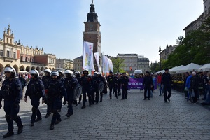 umundurowani policjanci idący przed osobami uczestniczącymi w marszu na krakowskim Rynku Głównym