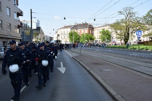 umundurowani policjanci idący przed uczestnikami marszu na jednej z krakowskich ulic