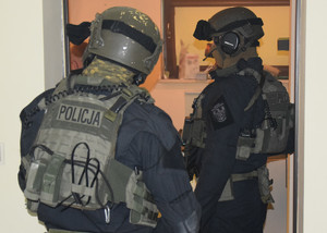 dwóch policjantów z pododdziału kontrterorystcznego policji stojących w drzwiach mieszkania