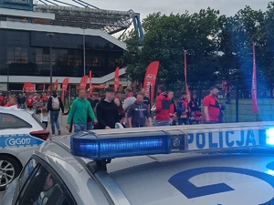 policyjne sygnały świetlne w tle których widać kibiców opuszczających rejon stadionu Wisły Kraków